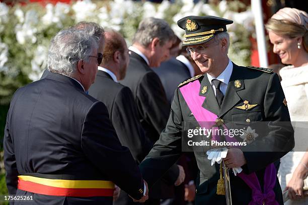 King Philippe of Belgium shakes hands witha guest during the Military Parade on July 21, 2013 in Brussels, Belgium.