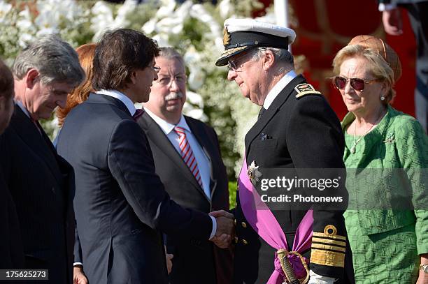 King Albert II shaking hands with Prime Minister Elio Di Rupo and Queen Paola during the Military Parade on July 21, 2013 in Brussels, Belgium.