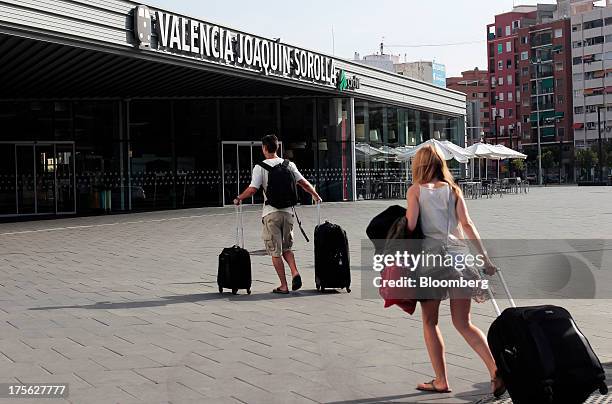 Passengers pull their luggage as they arrive outside Joaquin Sorolla railway station in Valencia, Spain, on Saturday, Aug. 3, 2013. Spain's...