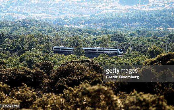 Train operated by Renfe Operadora SC travels past woodland near El Escorial, in northern Madrid, Spain, on Sunday, Aug. 4, 2013. Spain's state-owned...