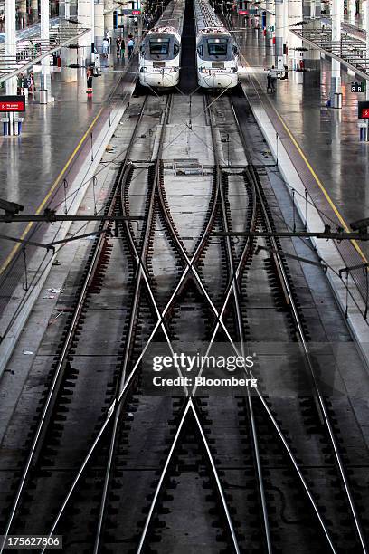 Two trains operated by Renfe Operadora SC sit beside platforms at Atocha train station in Madrid, Spain, on Saturday, Aug. 3, 2013. Spain's...