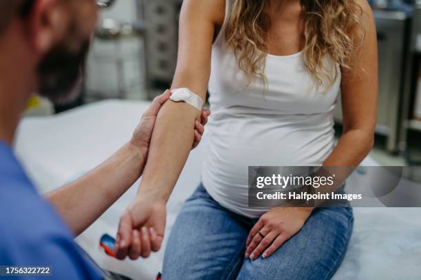 obstetrician gynaecologist taking blood sample from pregnant woman as a part of prenatal care, visit. pregnant woman on pregnancy check-up in doctor’s office. - testen antistoffen stockfoto's en -beelden