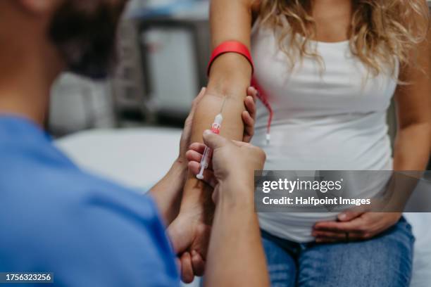 obstetrician gynaecologist taking blood sample from pregnant woman  as a part of prenatal care, visit. pregnant woman on pregnancy check-up in doctor’s office. gestational diabetes test. - baby in the womb stock pictures, royalty-free photos & images