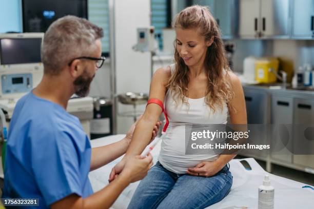 obstetrician gynaecologist taking blood sample from pregnant woman  as a part of prenatal care, visit. pregnant woman on pregnancy check-up in doctor’s office. gestational diabetes test. - baby in the womb stock pictures, royalty-free photos & images