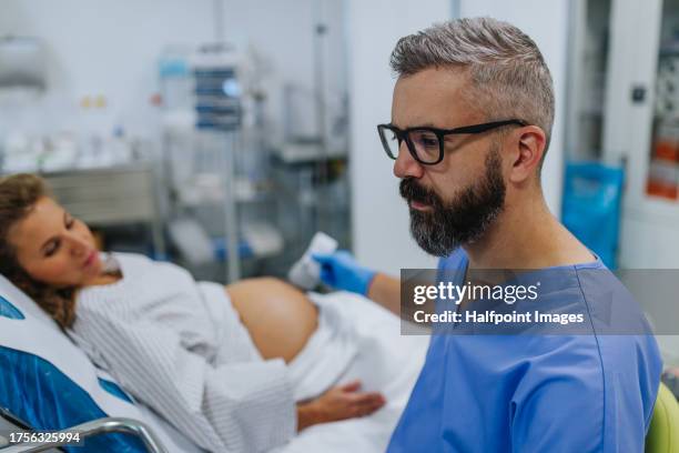 ob/gyn doctor doing ultrasound of baby on pregnant woman. woman having sonogram. prenatal visit or care during third trimester of pregnancy. pregnant woman on pregnancy check-up in doctor’s office. - baby in the womb stock pictures, royalty-free photos & images