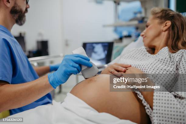 ob/gyn doctor doing ultrasound of baby on pregnant woman. woman having sonogram. prenatal visit or care during third trimester of pregnancy. pregnant woman on pregnancy check-up in doctor’s office. - human reproductive organ stock pictures, royalty-free photos & images