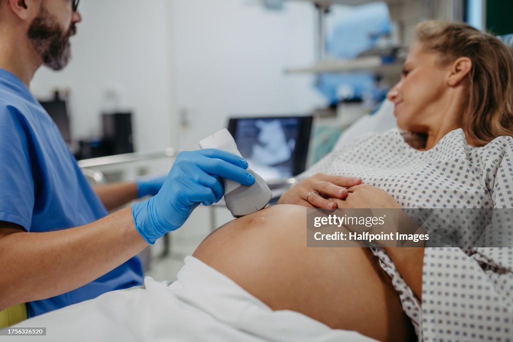 Ob/gyn doctor doing ultrasound of baby on pregnant woman. Woman having sonogram. Prenatal visit or care during third trimester of pregnancy. Pregnant woman on pregnancy check-up in doctor’s office.