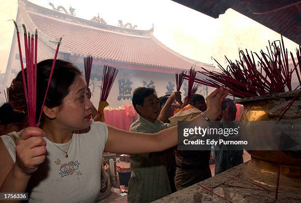 Member of Indonesian Chinese community holds incense as she prays during celebrations of the Lunar Chinese new year February 1, 2003 at a temple in...