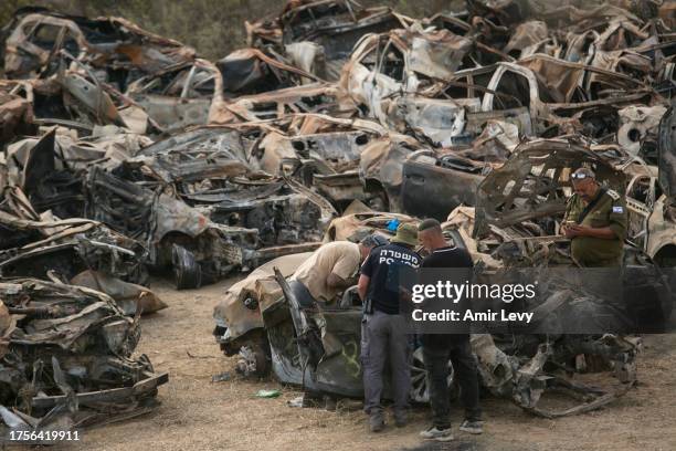 Police officers check cars that were burnt during Hamas' attack on the Israeli south border at a site where police collect damaged and burnt cars...