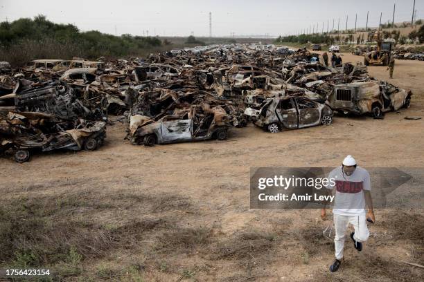 Man walks by cars that were burnt during Hamas' attack on the Israeli south border at a site where police collect damaged and burnt cars from the...