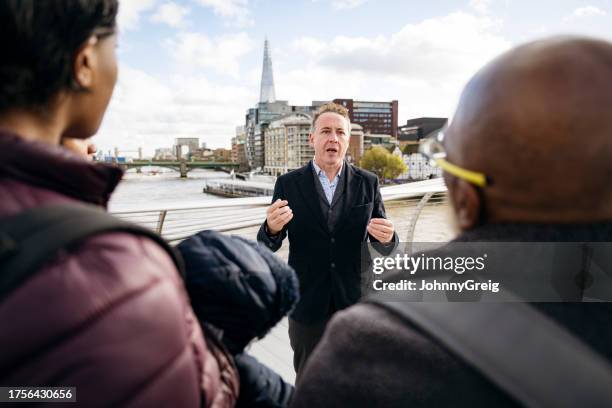 london tour guide talking to tourists by river thames - history lesson stock pictures, royalty-free photos & images