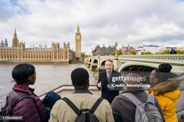british tour guide talking to tourists by houses of parliament - urban exploration stock pictures, royalty-free photos & images