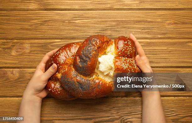 cropped hands of woman holding bread on table - challah stock pictures, royalty-free photos & images