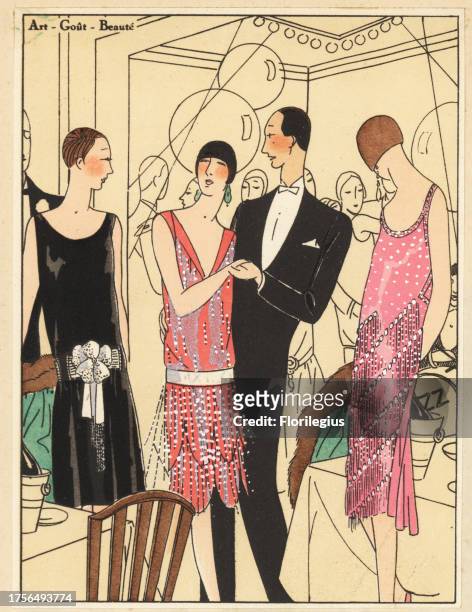 People at a fashionable party dancing to jazz. Women in evening dresses of black velvet, pink lame, and pink crepe georgine decorated with pearls and...