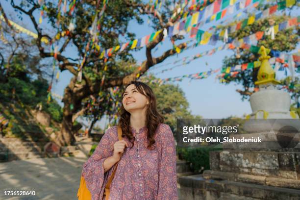 mujer de pie bajo banderas tibetanas de oración - valle de kathmandu fotografías e imágenes de stock