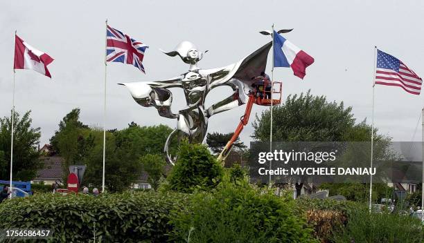 Des persones travaillent, le 31 mai 2004 à l'entrée de Grandcamp-Maisy, à la mise en place de la "Victoire de la paix", une statue en inox de 10...