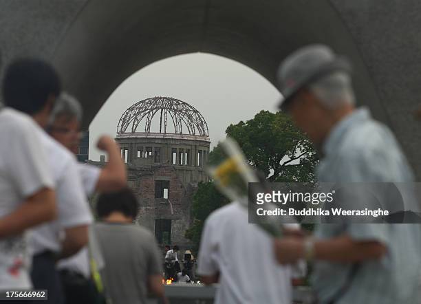 People pray in front of a monument for atomic bomb victims at the Hiroshima Peace Memorial Park on the day of the 68th anniversary of the atomic...