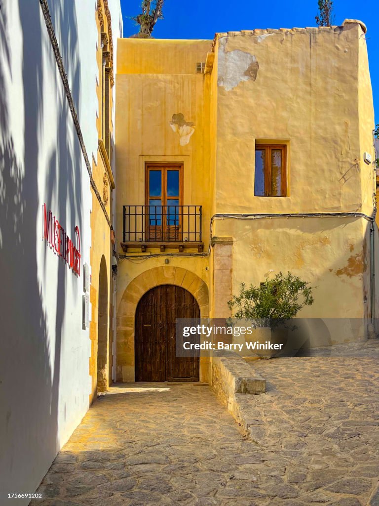 People near entrance to Puget Museum, with huge palm tree shadow on wall, in Ibiza