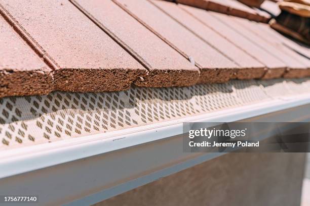 grille de protection protégeant une gouttière en aluminium des débris sur un toit en tuiles d’argile sur une maison résidentielle du sud-ouest des états-unis - garder photos et images de collection