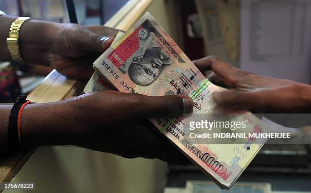 Customer receives a wad of Indian rupee notes from a foreign exchange dealer in Mumbai on August 6, 2013. India's rupee plunged to a fresh record low...