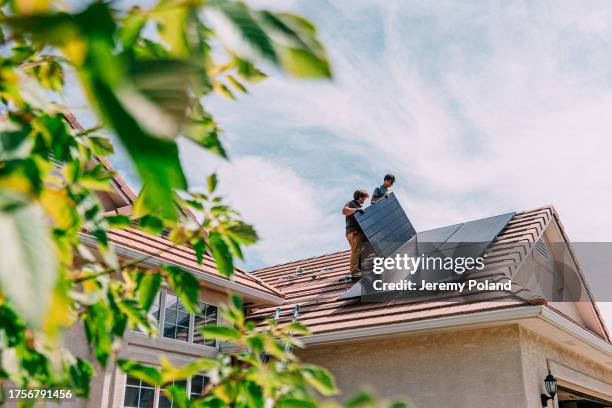 go green: young homeowners installing solar panels on a suburban western usa home - equipamento industrial imagens e fotografias de stock