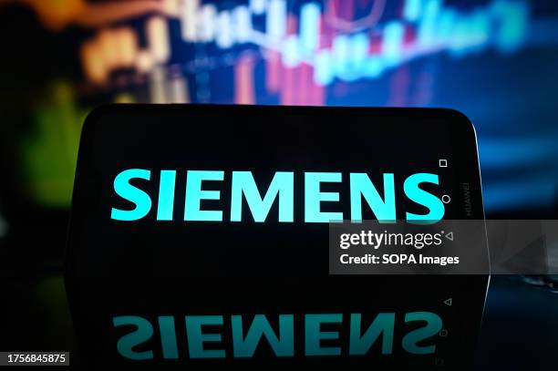In this photo illustration a Siemens logo is displayed on a smartphone with stock market percentages in the background.