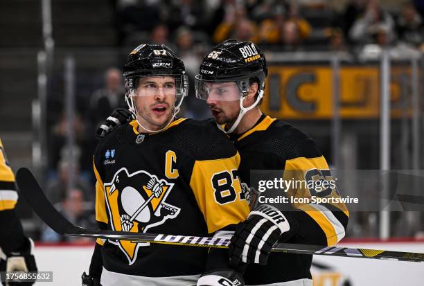 Pittsburgh Penguins defenseman Erik Karlsson talks to Pittsburgh Penguins center Sidney Crosby during a break in the second period in the NHL game...