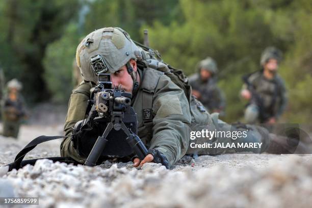 An Israeli army soldier looks through the scope of a rifle while lying prone at a position in the upper Galilee region of northern Israel near the...