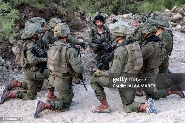 Israeli army soldiers sit kneeling at a position in the upper Galilee region of northern Israel near the border with Lebanon on November 1, 2023 amid...