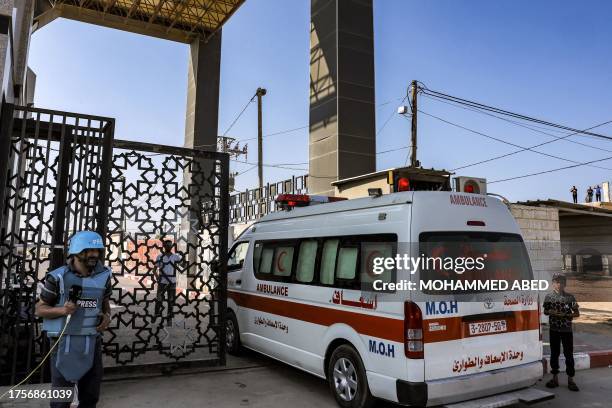 Journalist stands by as Palestinian health ministry ambulances cross the gate to enter the Rafah border crossing in the southern Gaza Strip before...