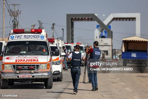 Journalists film as Palestinian health ministry ambulances cross the gate to enter the Rafah border crossing in the southern Gaza Strip before...