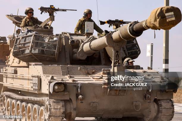 Israeli army soldiers sit in the turret of a self-propelled artillery howitzer moving on a road along the border with the Gaza Strip in southern...