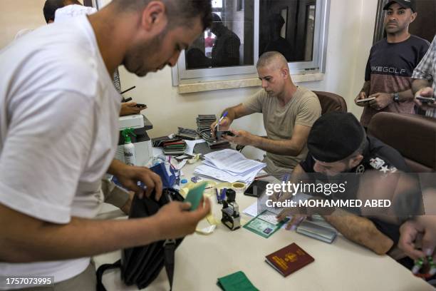Palestinian passport control policemen affiliated with Hamas check the travel documents of people waiting to cross to Egypt at the Rafah border...