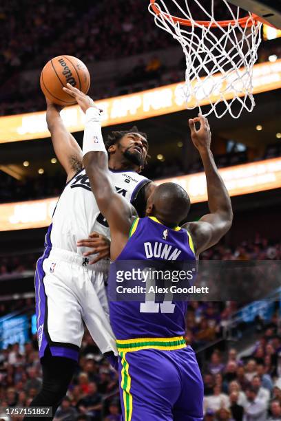 Malik Monk of the Sacramento Kings dunks over Kris Dunn of the Utah Jazz during the second half of a game at Delta Center on October 25, 2023 in Salt...