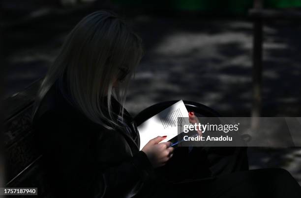 Woman reads a book on a sunny day during autumn season at Kugulu Park, in Turkiye on November 01, 2023.