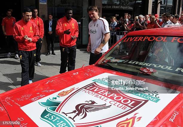 Kolo Toure and Oussama Assaidi of Liverpool autographs a car decorated by Liverpool fan Jan Erik Andersen outside the Clarion Hotel on August 7, 2013...
