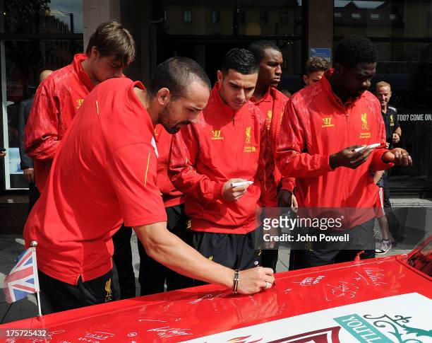 Kolo Toure, Oussama Assaidi and Jose Enrique of Liverpool autographs a car decorated by Liverpool fan Jan Erik Andersen outside the Clarion Hotel on...