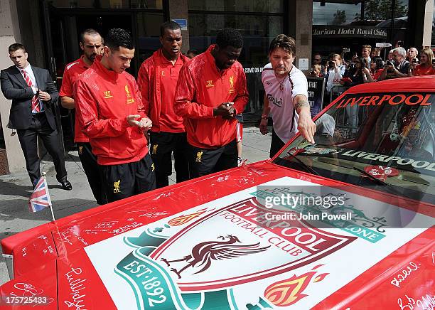 Kolo Toure and Oussama Assaidi of Liverpool autographs a car decorated by Liverpool fan Jan Erik Andersen outside the Clarion Hotel on August 7, 2013...