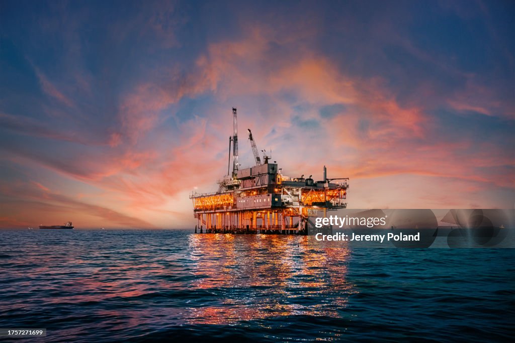 Vibrante cielo al atardecer detrás de una plataforma de perforación petrolera en alta mar frente a la costa del condado de Orange, California