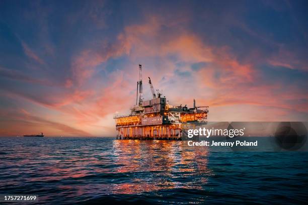 vibrante cielo al atardecer detrás de una plataforma de perforación petrolera en alta mar frente a la costa del condado de orange, california - oil and gas rig fotografías e imágenes de stock