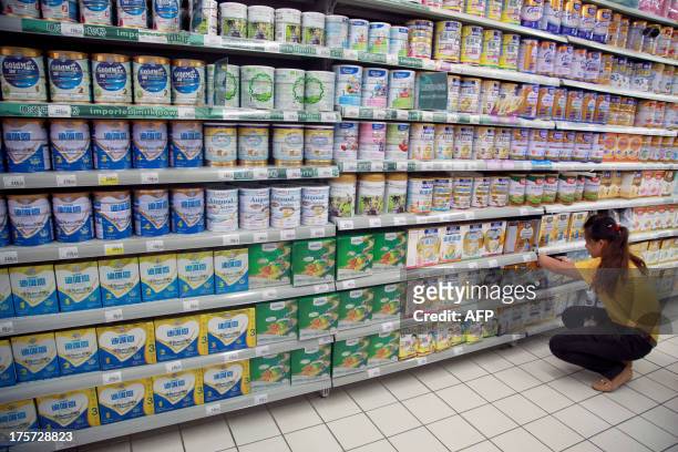 An employee works in front of shelves of baby milk in a supermarket in Haikou, in southern China's Hainan province on August 7, 2013. China has fined...