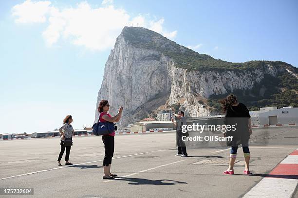 Holidaymakers take pictures of each other on the footpath which crosses Gibraltar's runway on August 7, 2013 in Gibraltar. Following talks between...