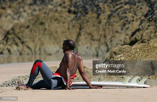 Surfer watches from the beach a heat of the Boardmasters pro-surfing competition on Fistral Beach on August 7, 2013 in Newquay, England. Since 1981,...