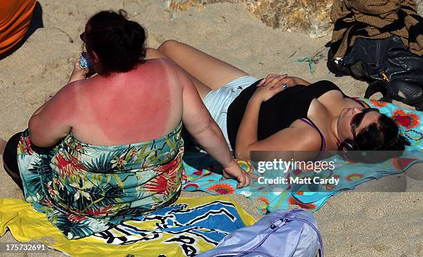 People sunbathe on the beach as the Boardmasters pro-surfing competition takes place on Fistral Beach on August 7, 2013 in Newquay, England. Since...