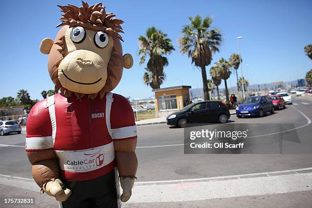 Person wearing a giant monkey costume advertising Gibraltar's cable car, stands adjacent to a queue of motorists waiting to cross the border with...