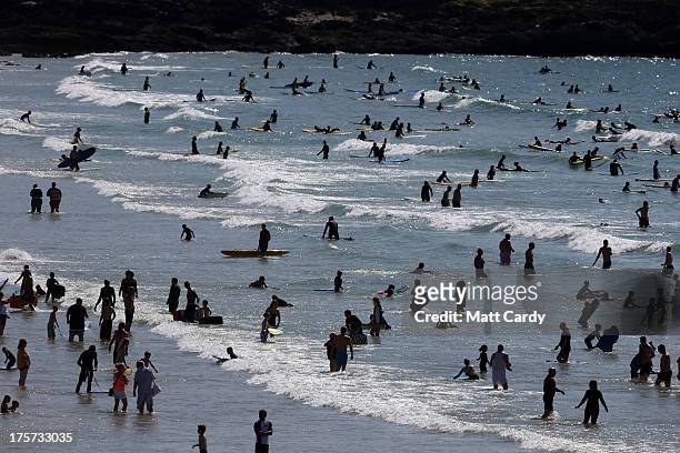 People swim, surf and bodyboard in the sea as Boardmasters pro-surfing competition takes place on Fistral Beach on August 7, 2013 in Newquay,...