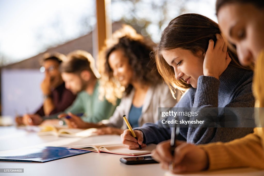 Lächelnder College-Student schreibt während eines Kurses an der Universität.