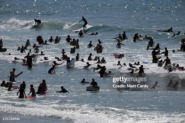 People swim, surf and bodyboard in the sea as Boardmasters pro-surfing competition takes place on Fistral Beach on August 7, 2013 in Newquay,...