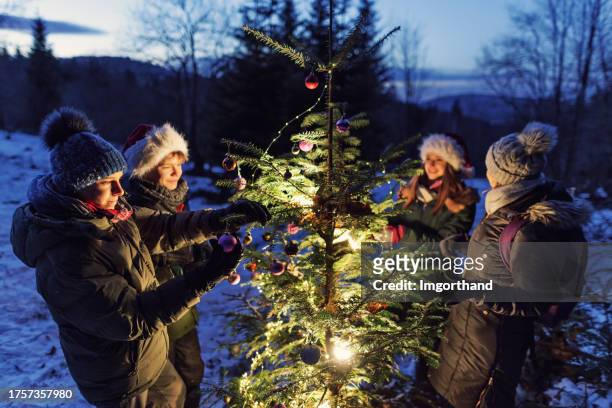 teenagers decorating a christmas tree in the forest - woman snow outside night stockfoto's en -beelden
