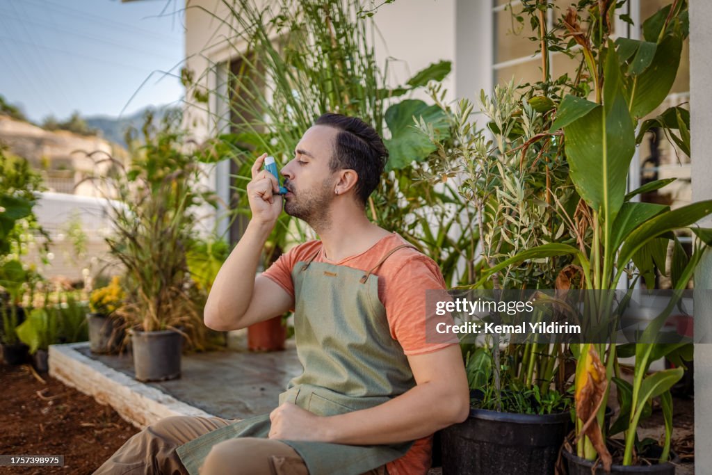 Young man using an asthma inhaler at outdoors
